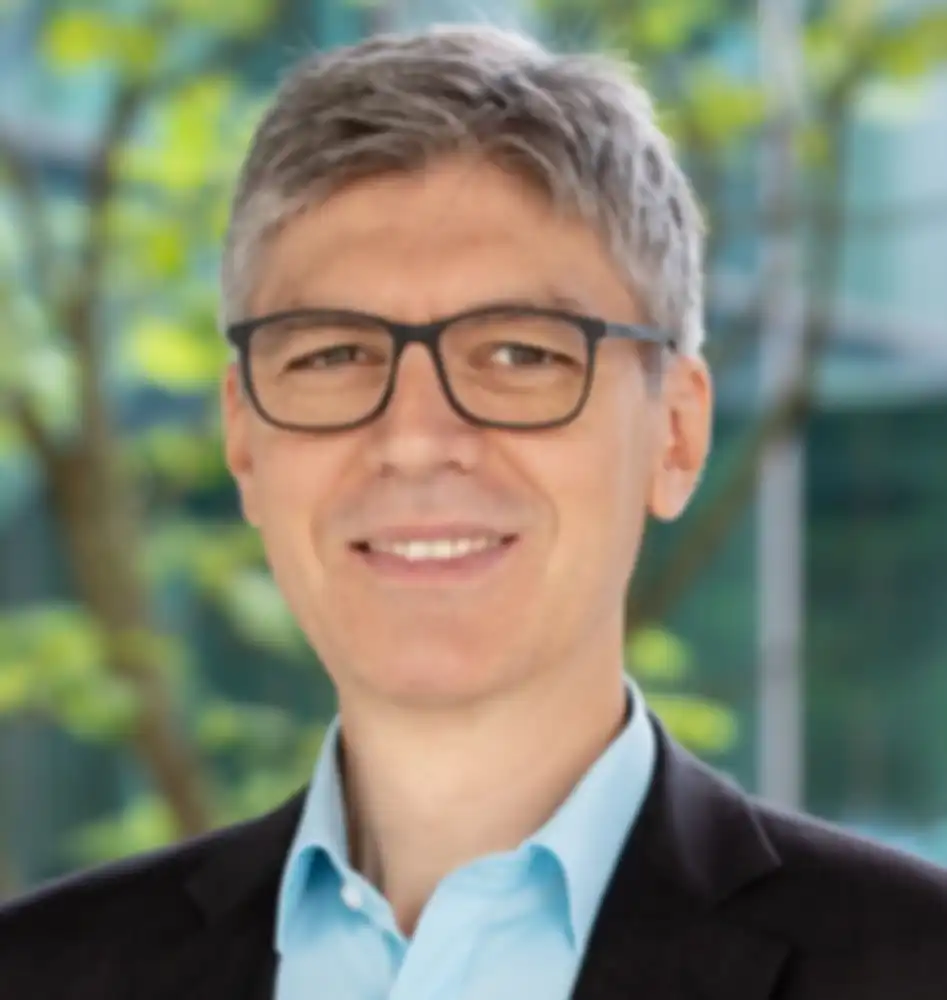 A portrait photo of Professor Albu-Schaeffer, smiling slightly against a background of blurred branches