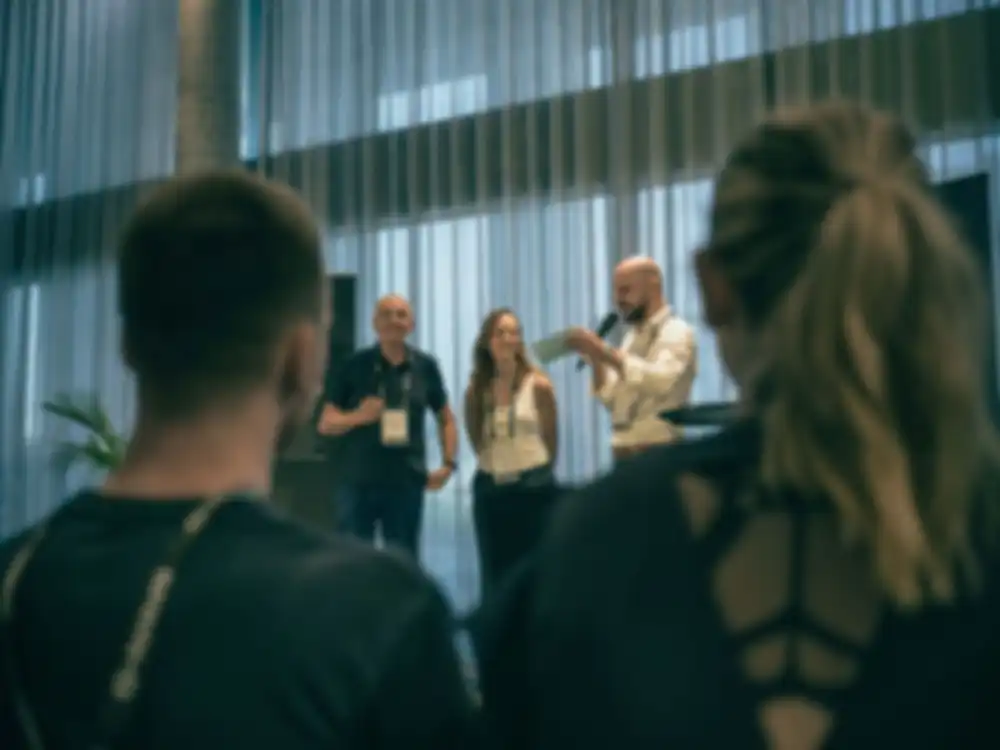 Three people stand on stage and talk about the project