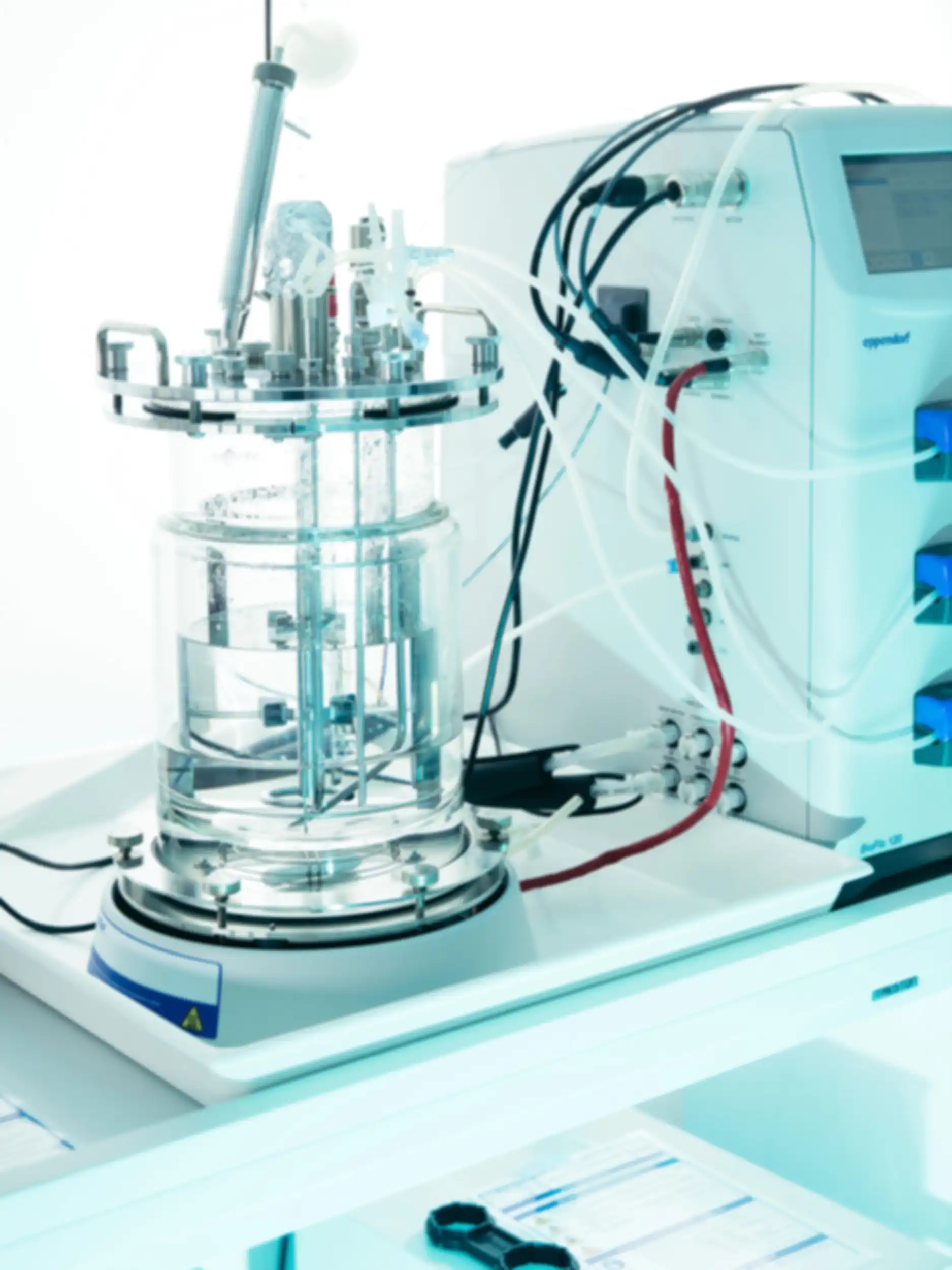 A piece of technical equipment with a glass body is connected to another piece of equipment by many tubes