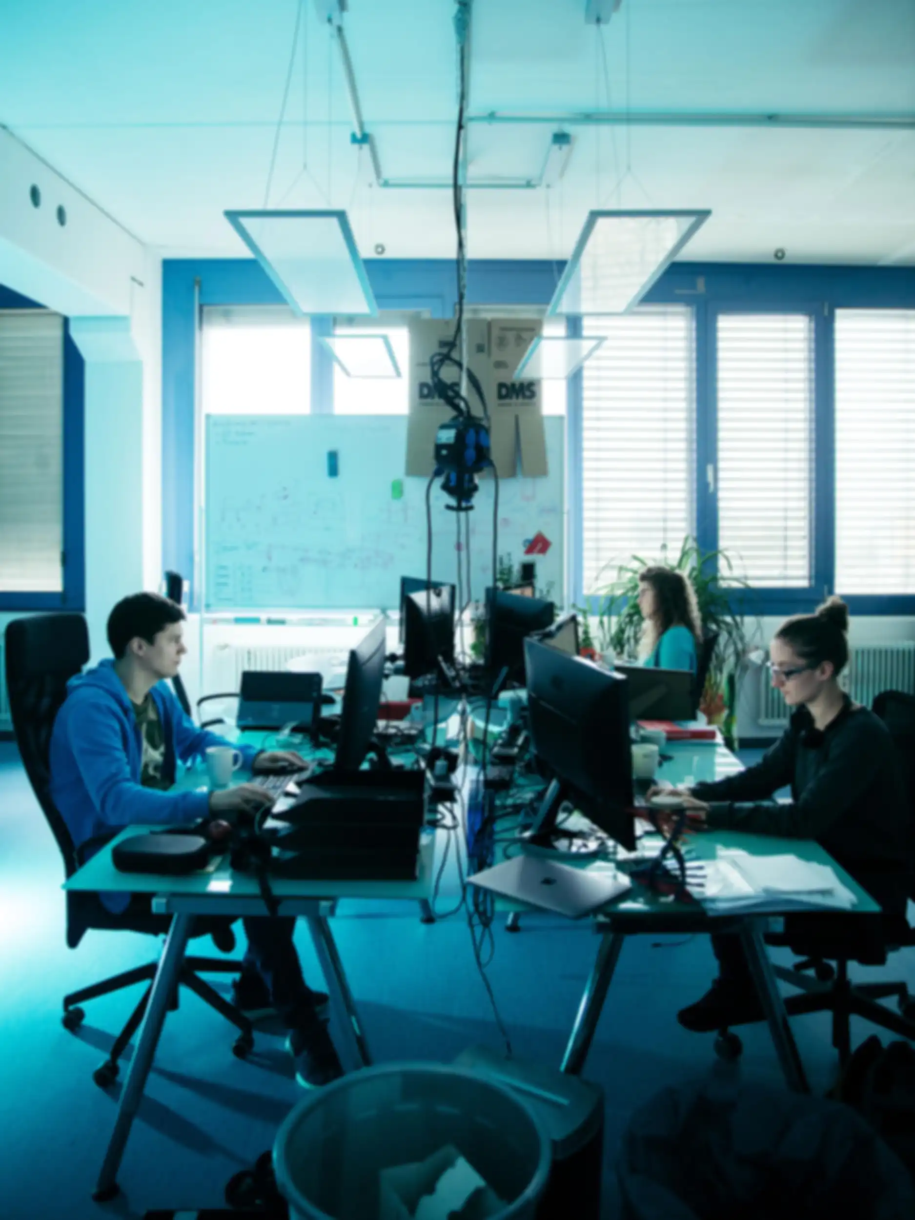 Several people are working at different computer screens in the Nanogami office