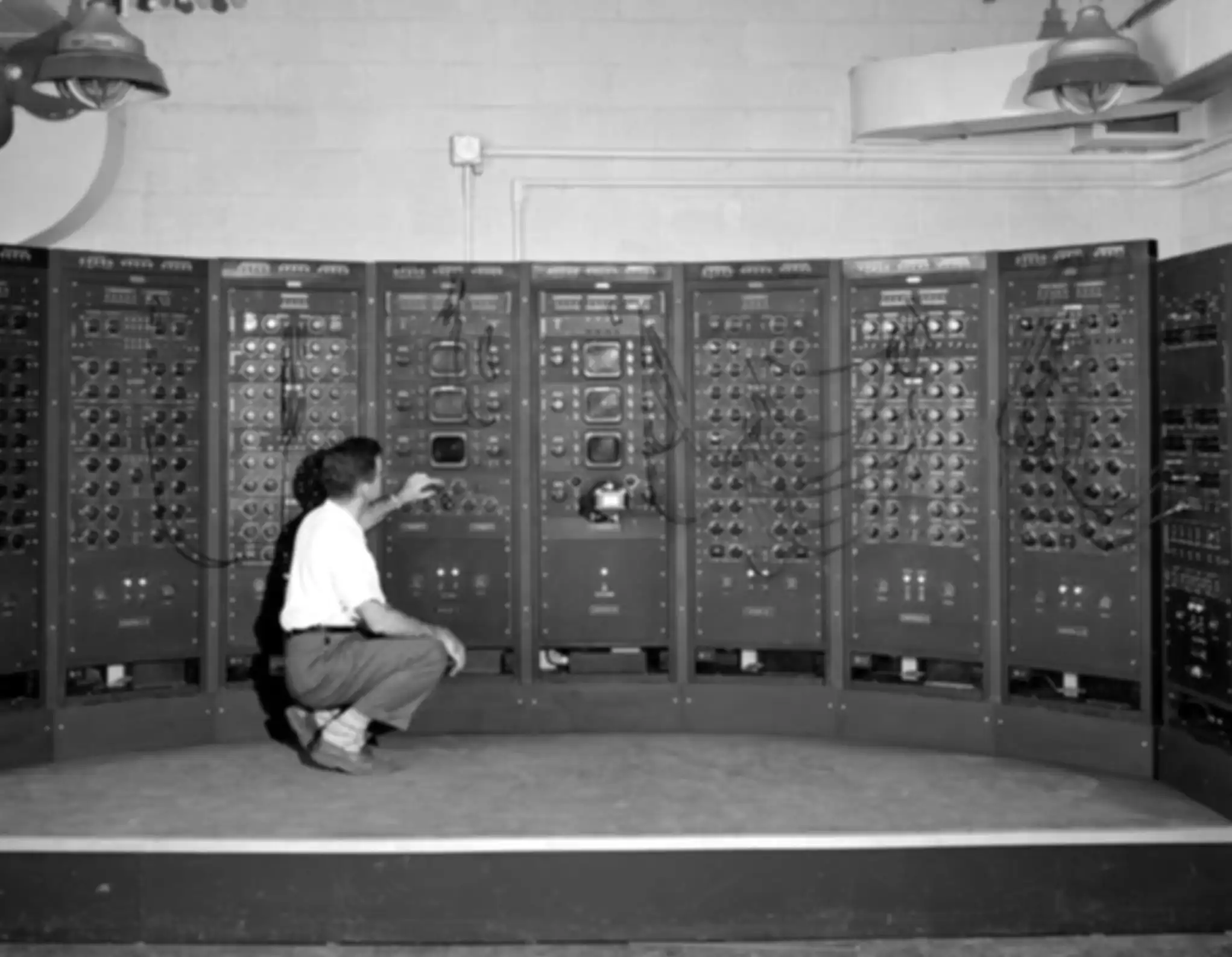 A man is kneeling in front of an analog computer
