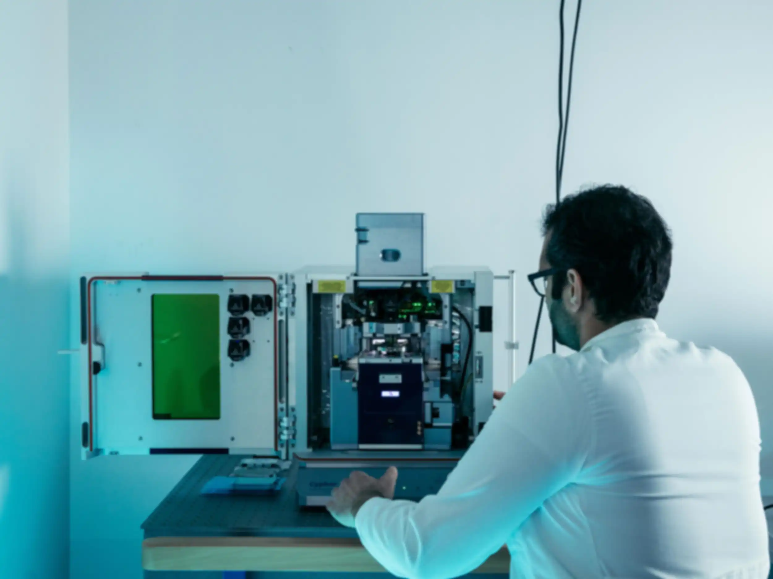 A man in a lab coat standing in front of an open rectangular piece of equipment