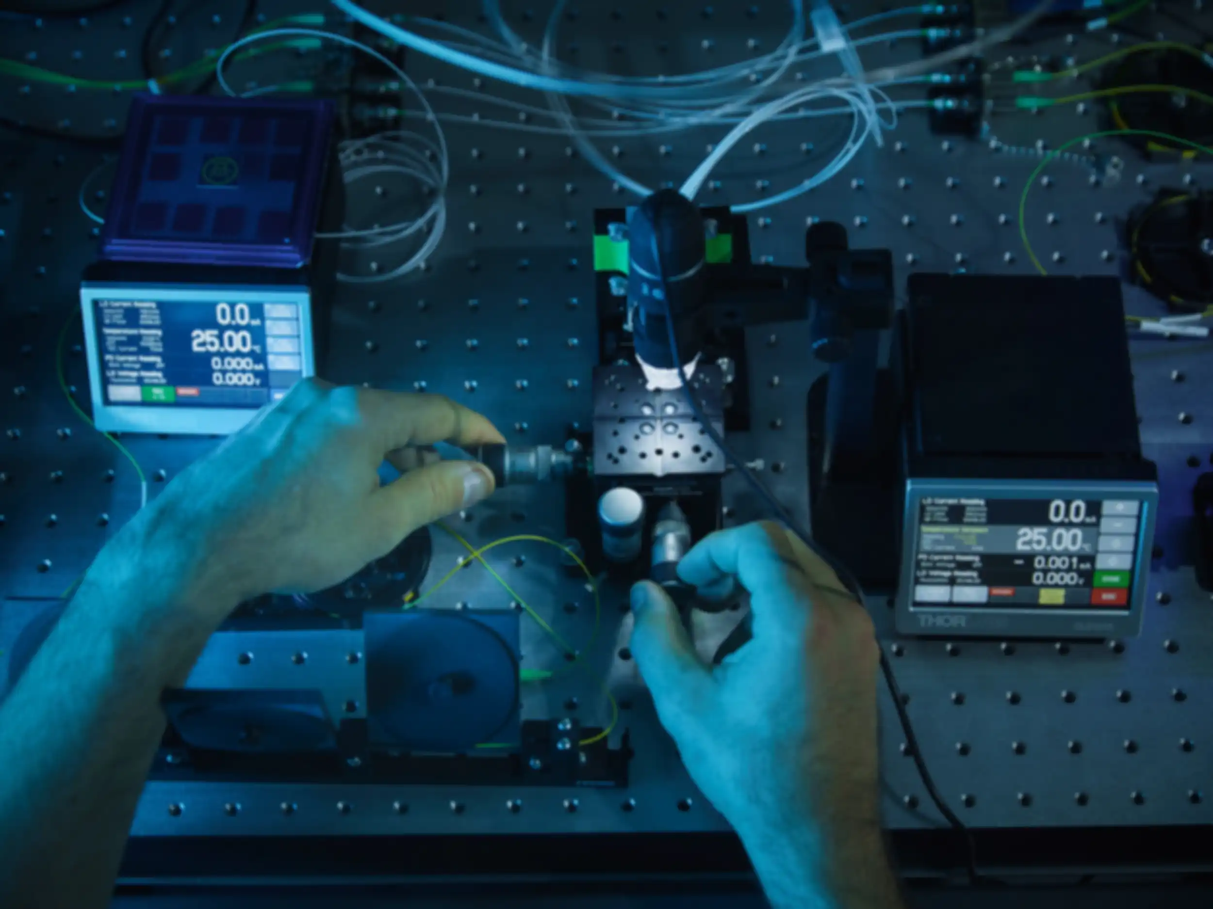 A person is operating two controls on a device connected to an experimental setup.