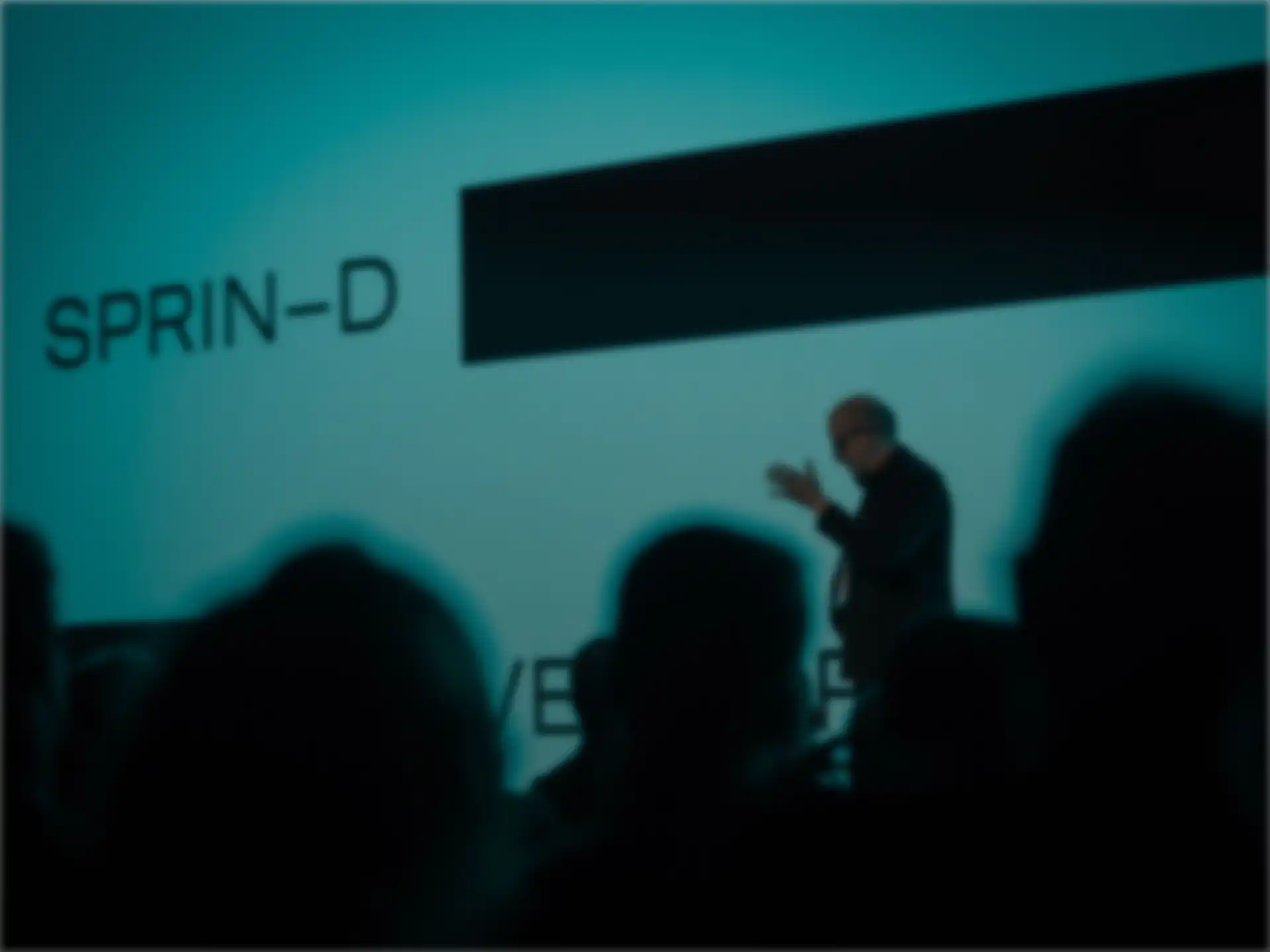 Rafael Laguna de la Vera is giving a presentation on stage. Behind him is a large SPRIND logo on a screen.