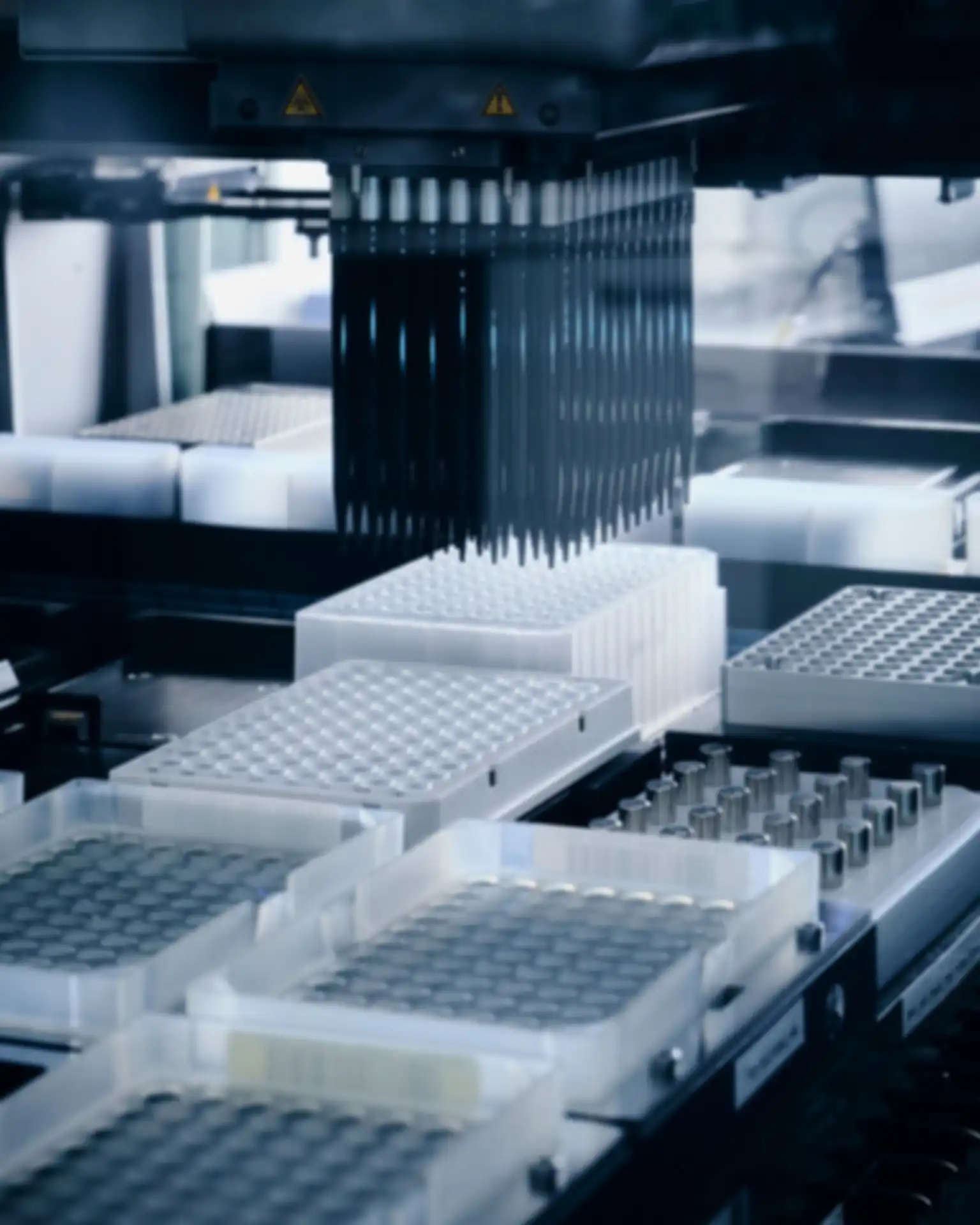 Several black pipettes are moved by a gripper arm. Among them are several holding devices.