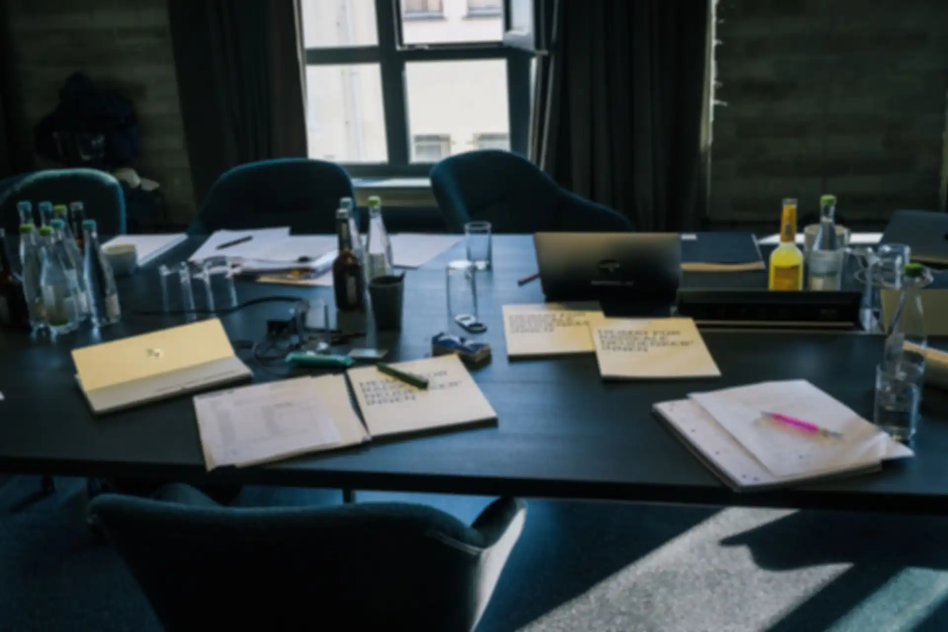 Various notepads and pens on a table in a conference room