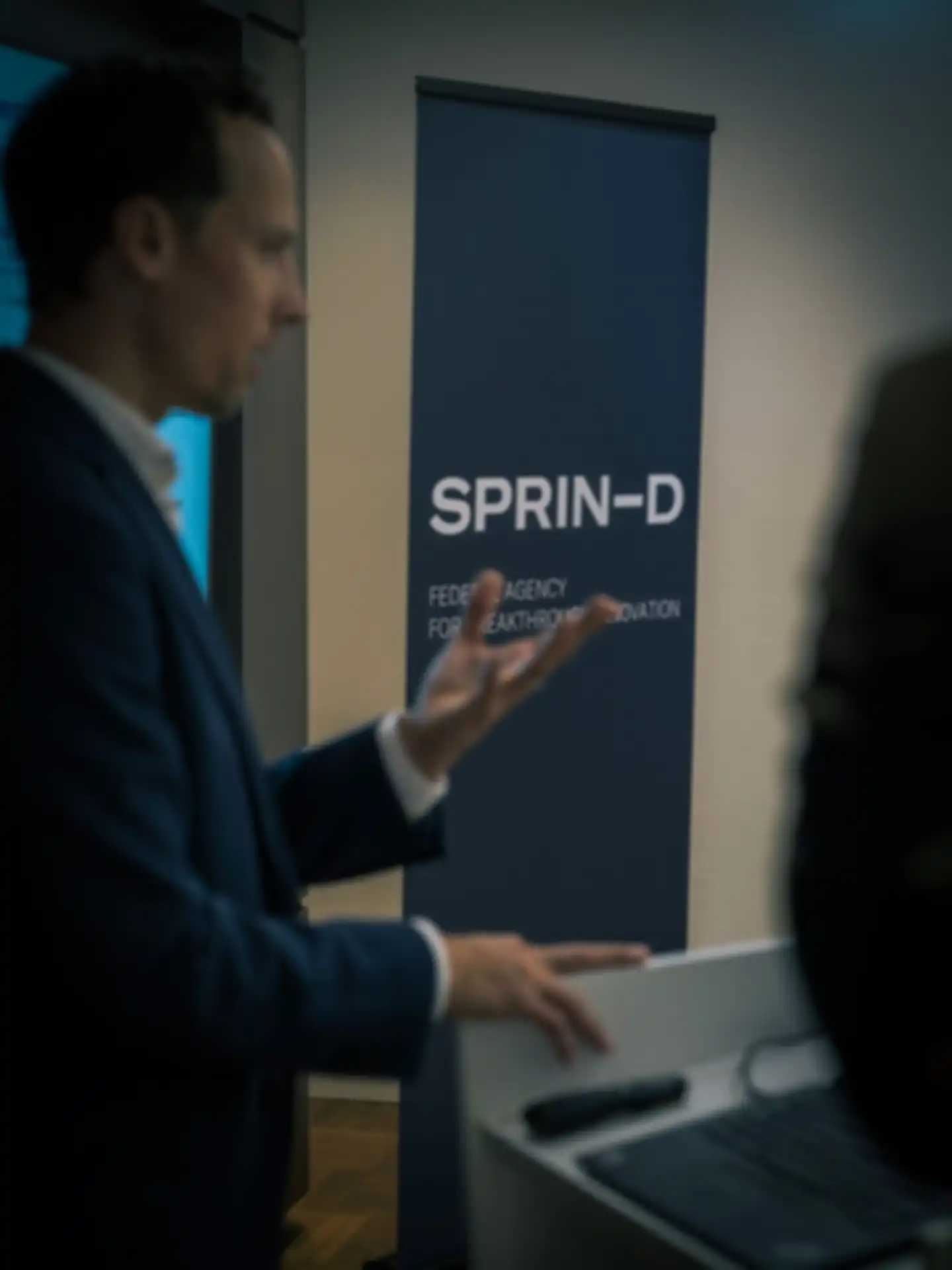 Ein Mann hält einen Vortrag. Im Hintergrund ein SPRIND Banner