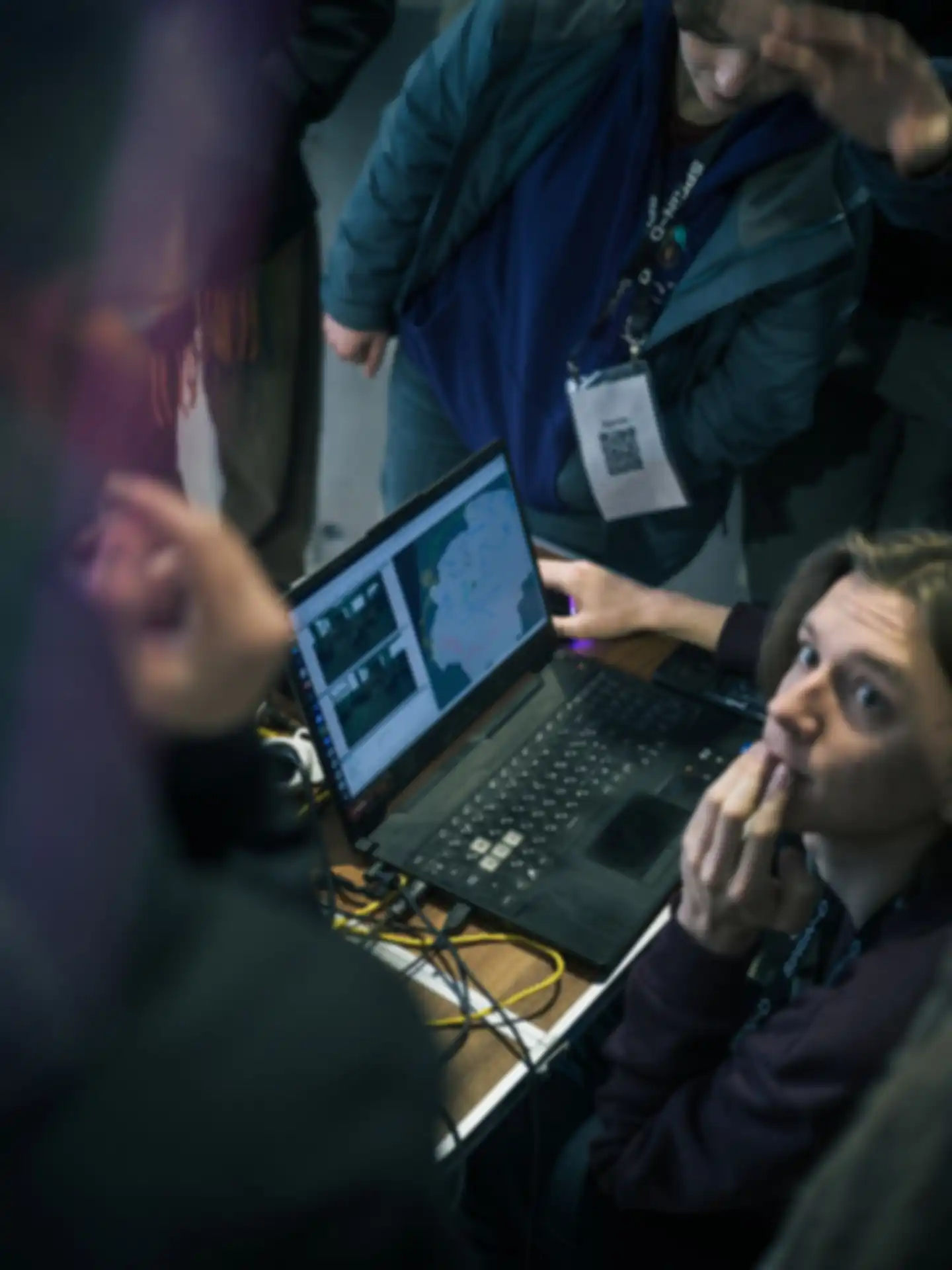 A team is having a discussion while one person sits in front of a laptop.