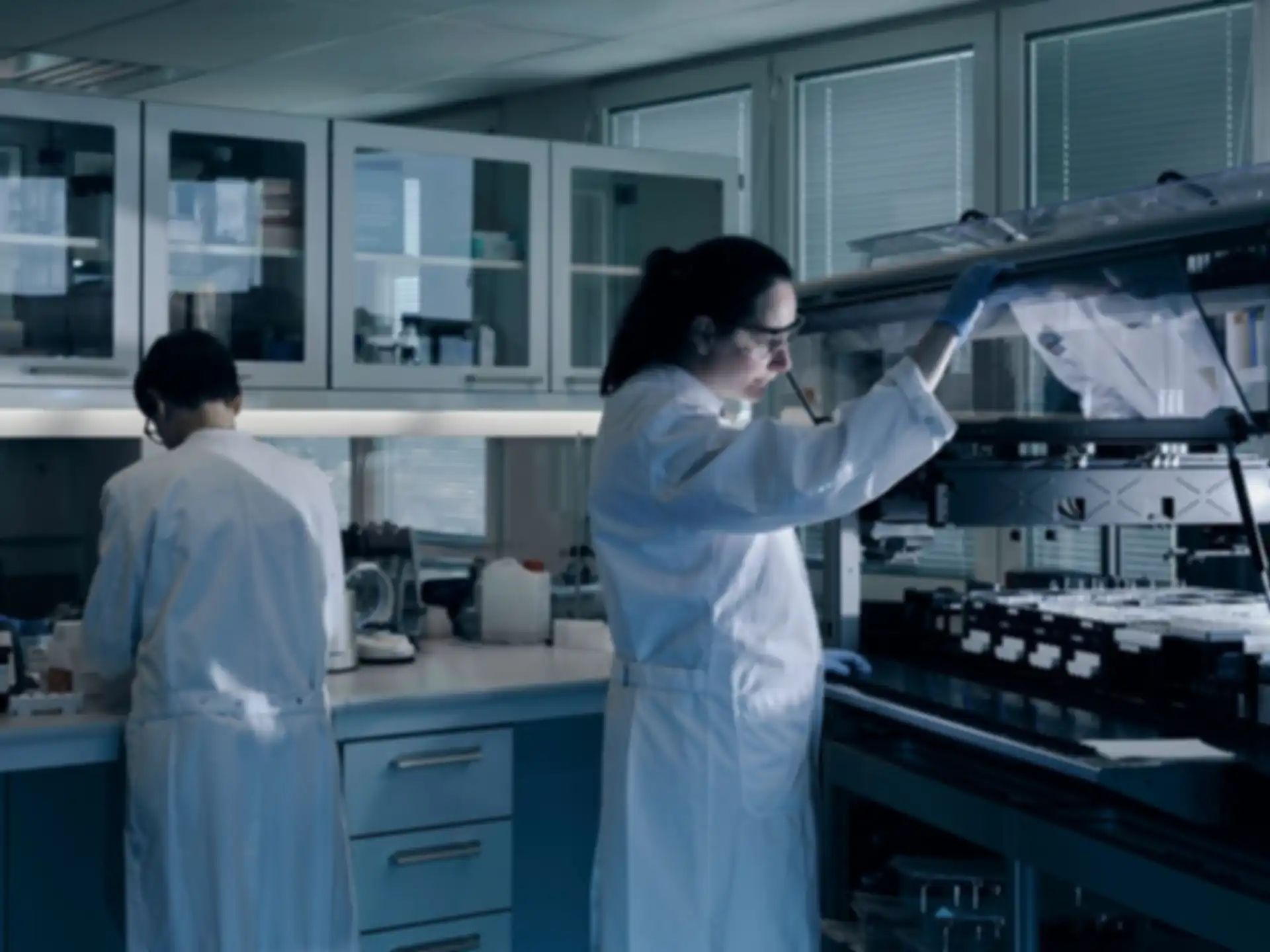 A woman and a man working in a laboratory. Both are wearing white lab coats.