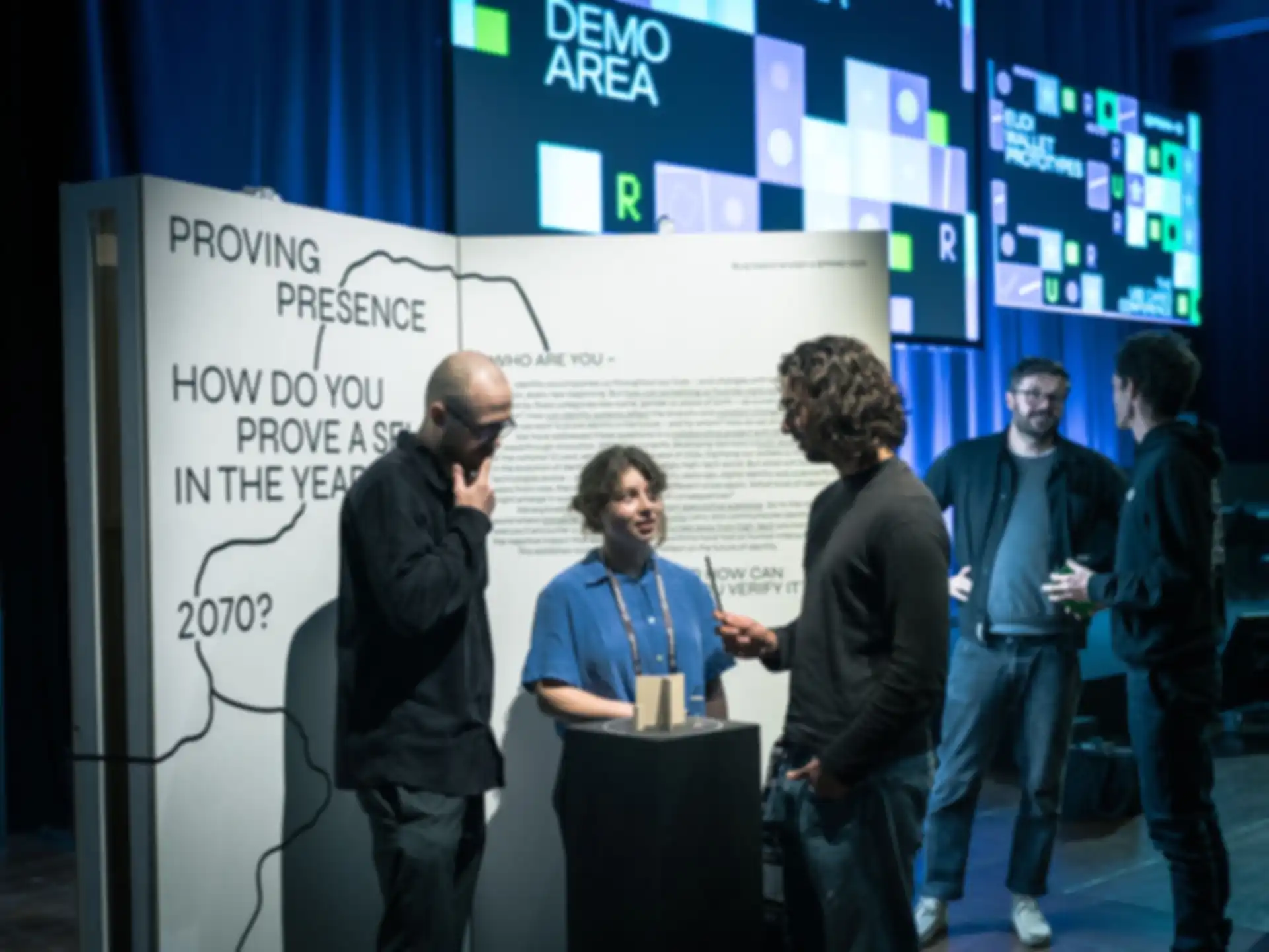 Three people are standing at the booth at the "EUDI Wallet Prototypes" Conference 2025