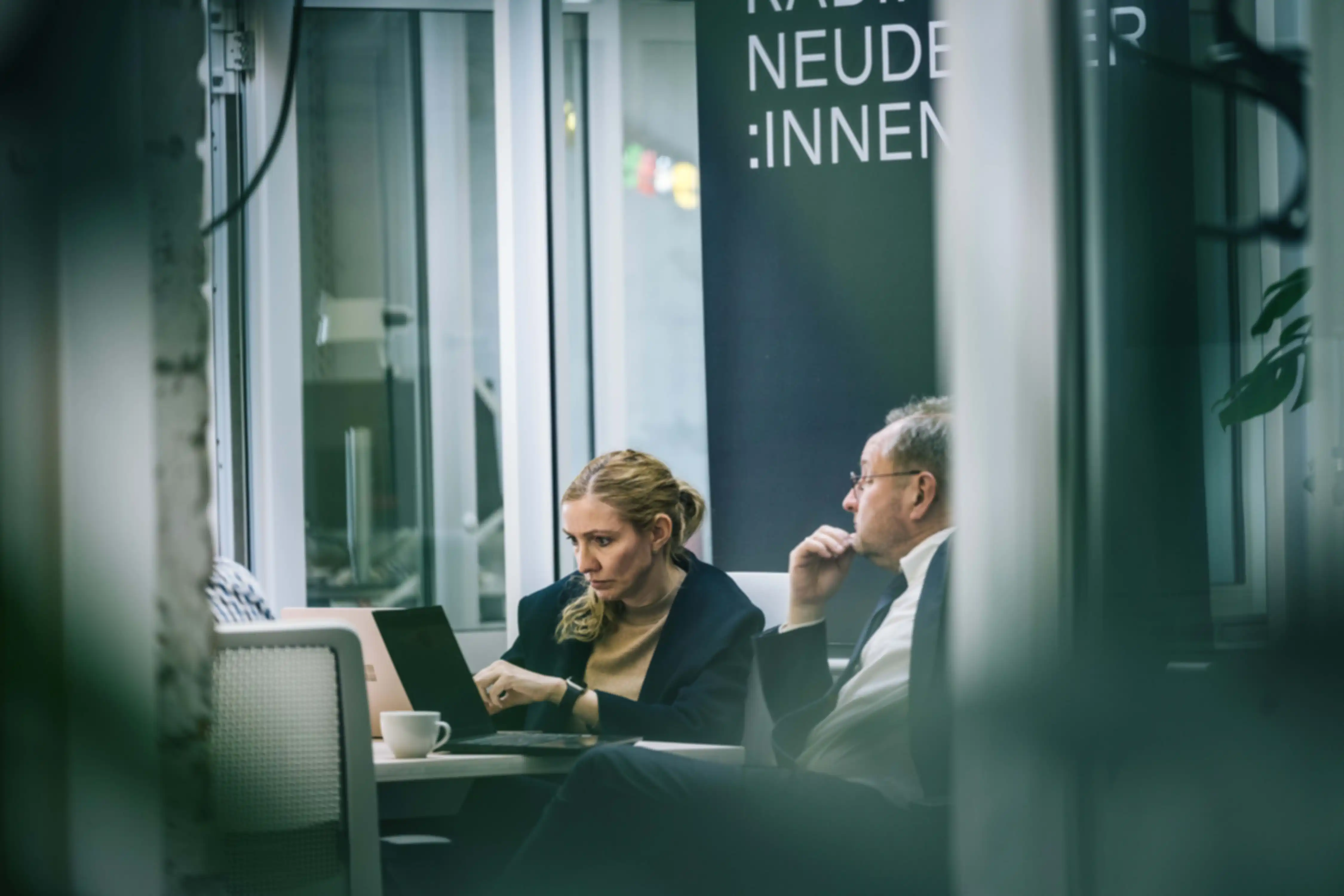 Zwei Personen im Gespräch. Gemeinsam schauen sie auf ein Laptop