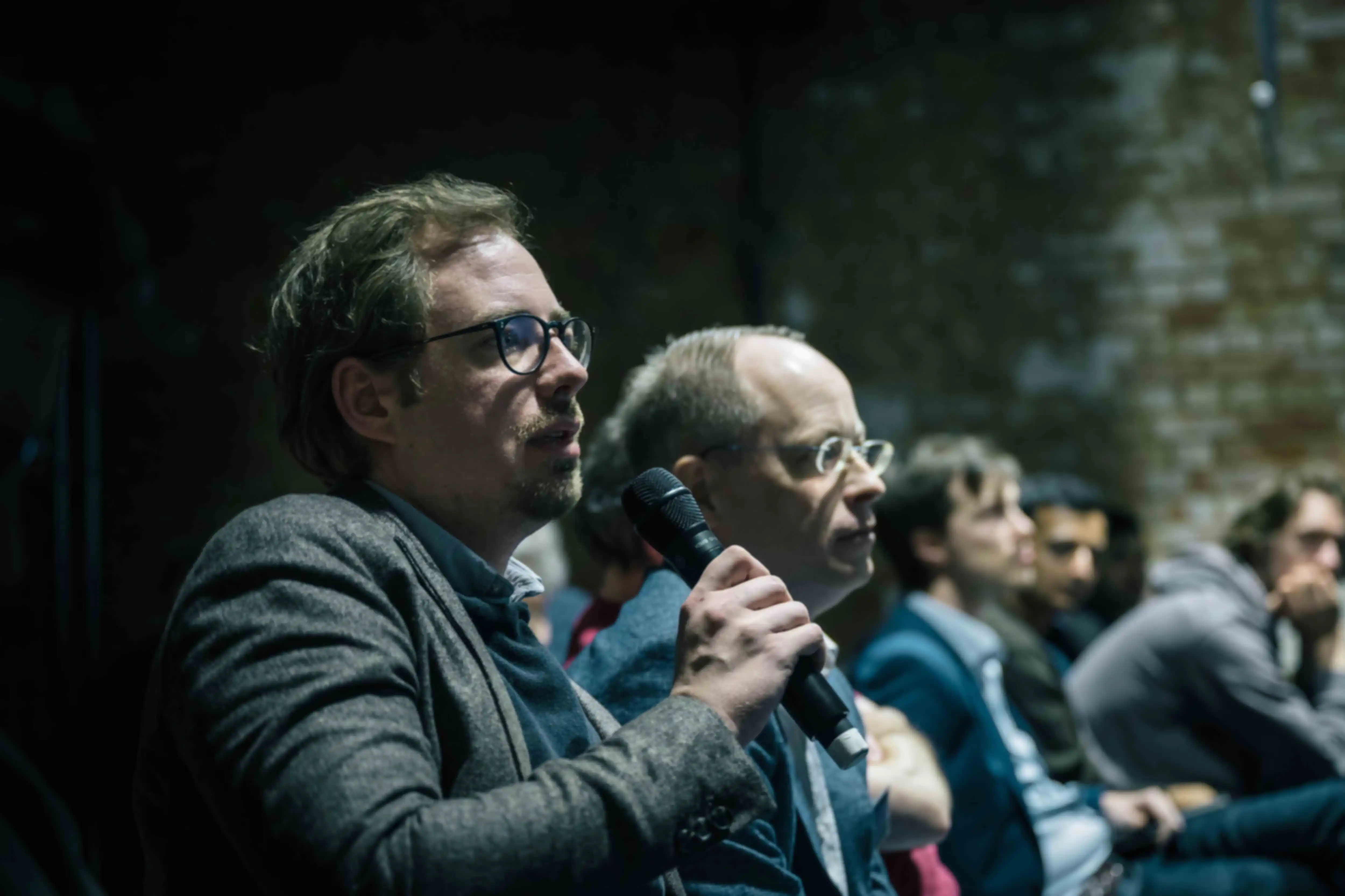 A person from the audience asks a question while holding a microphone