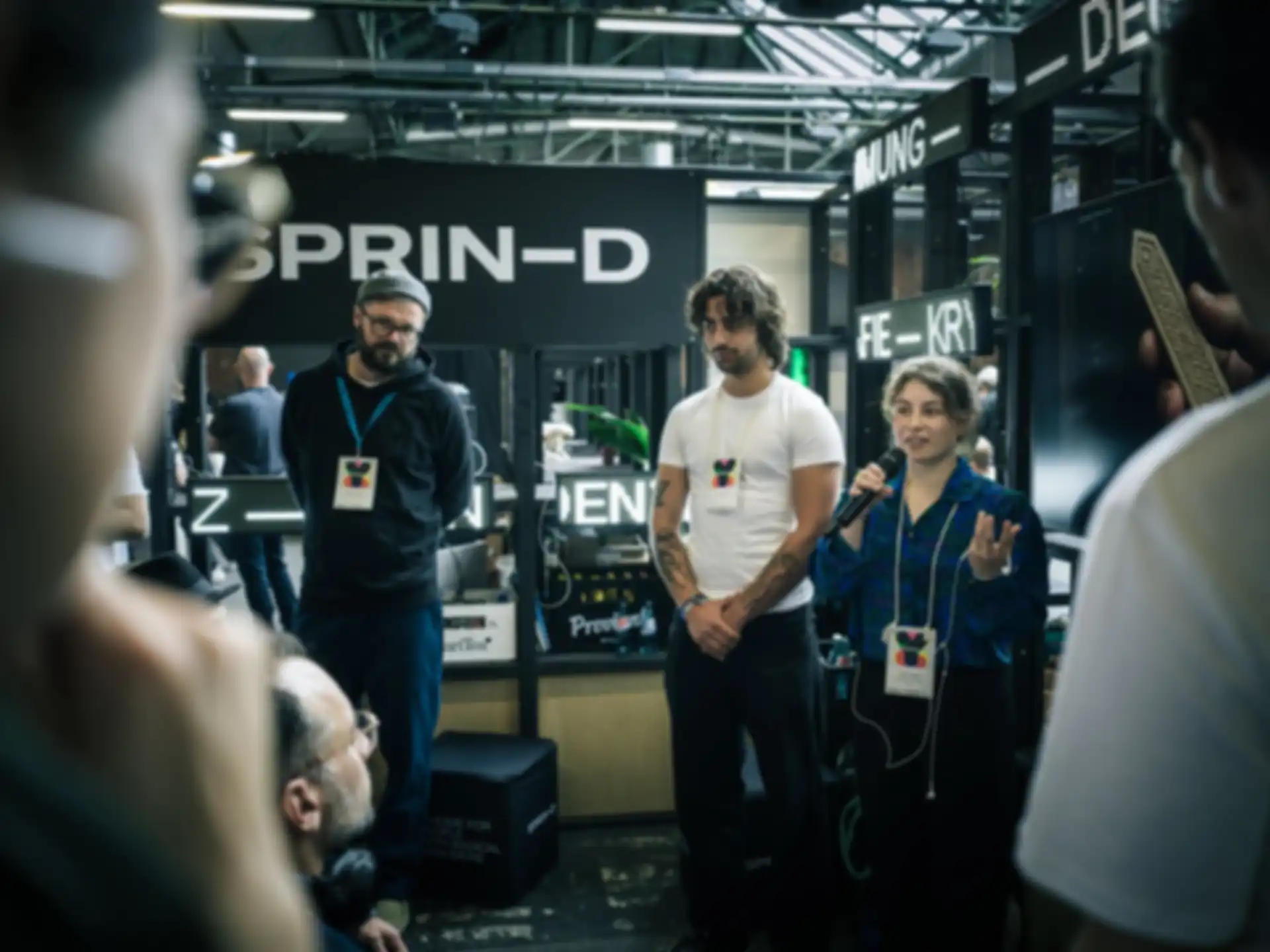 Three people are giving a presentation at a fair booth.