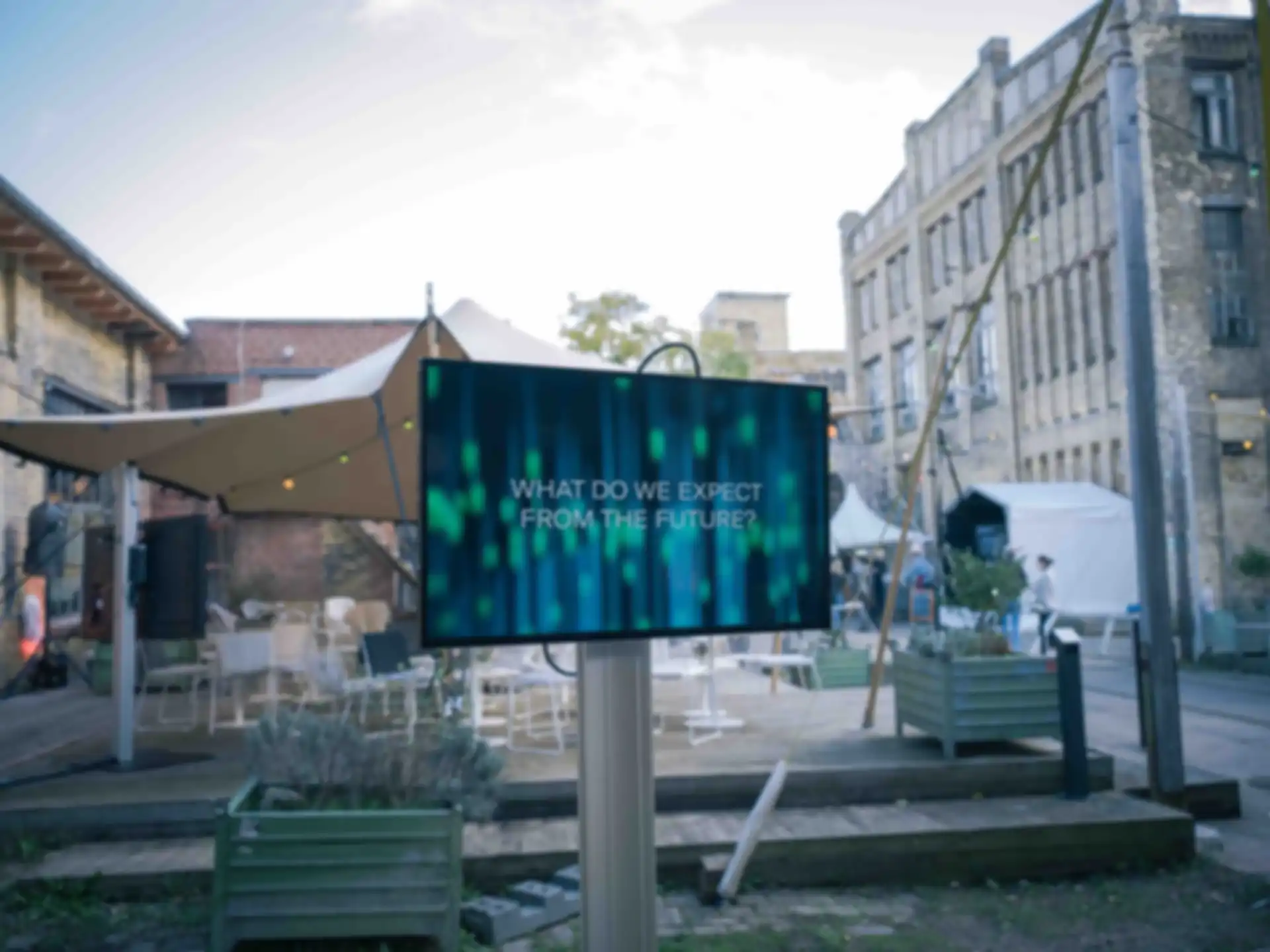 Ein Bildschirm im Außenbereich mit der Information "What do we expect from the future?"