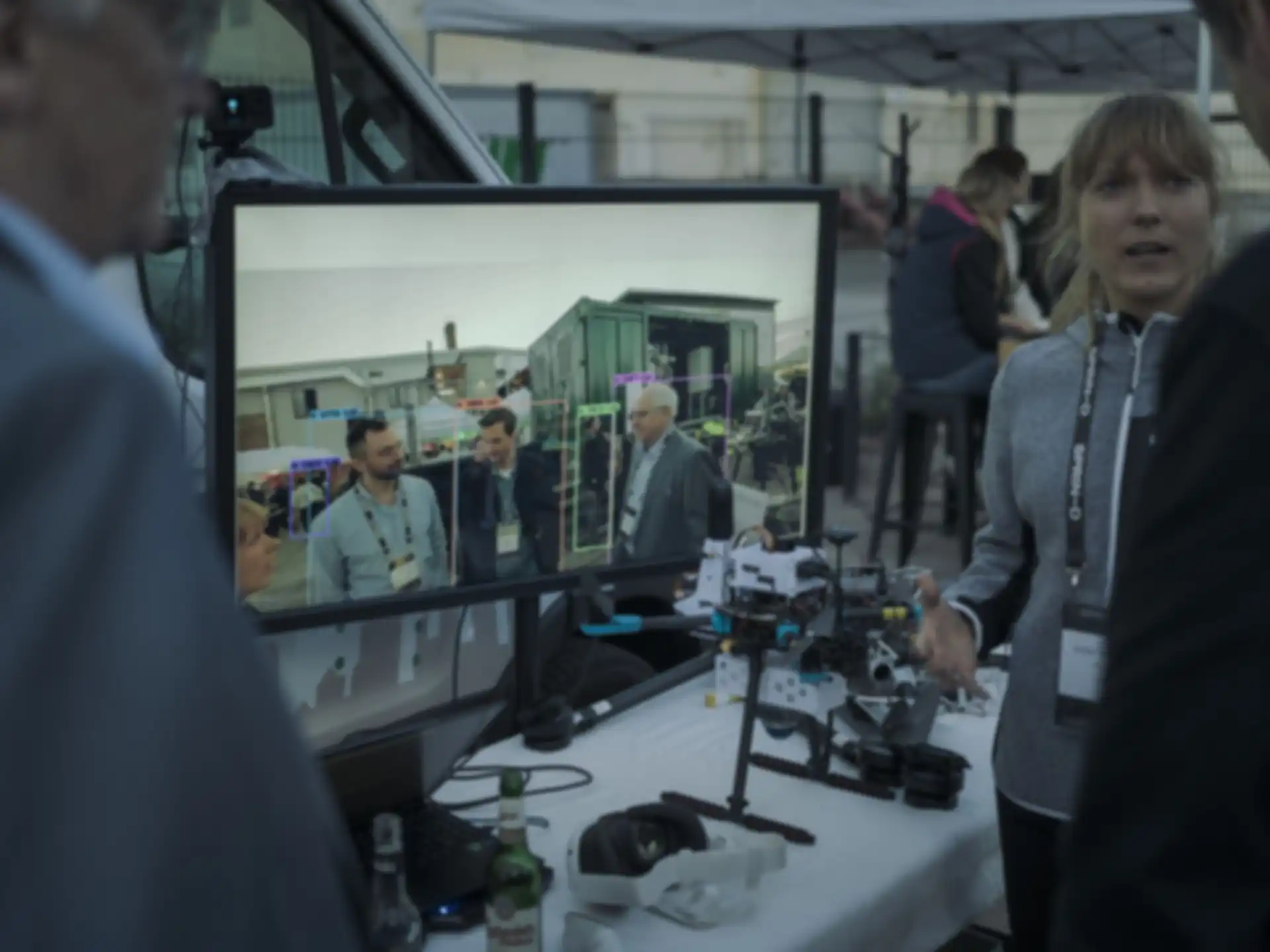 Mehrere Personen unterhalten sich auf einem Stand und stehen dabei um einen Monitor herum