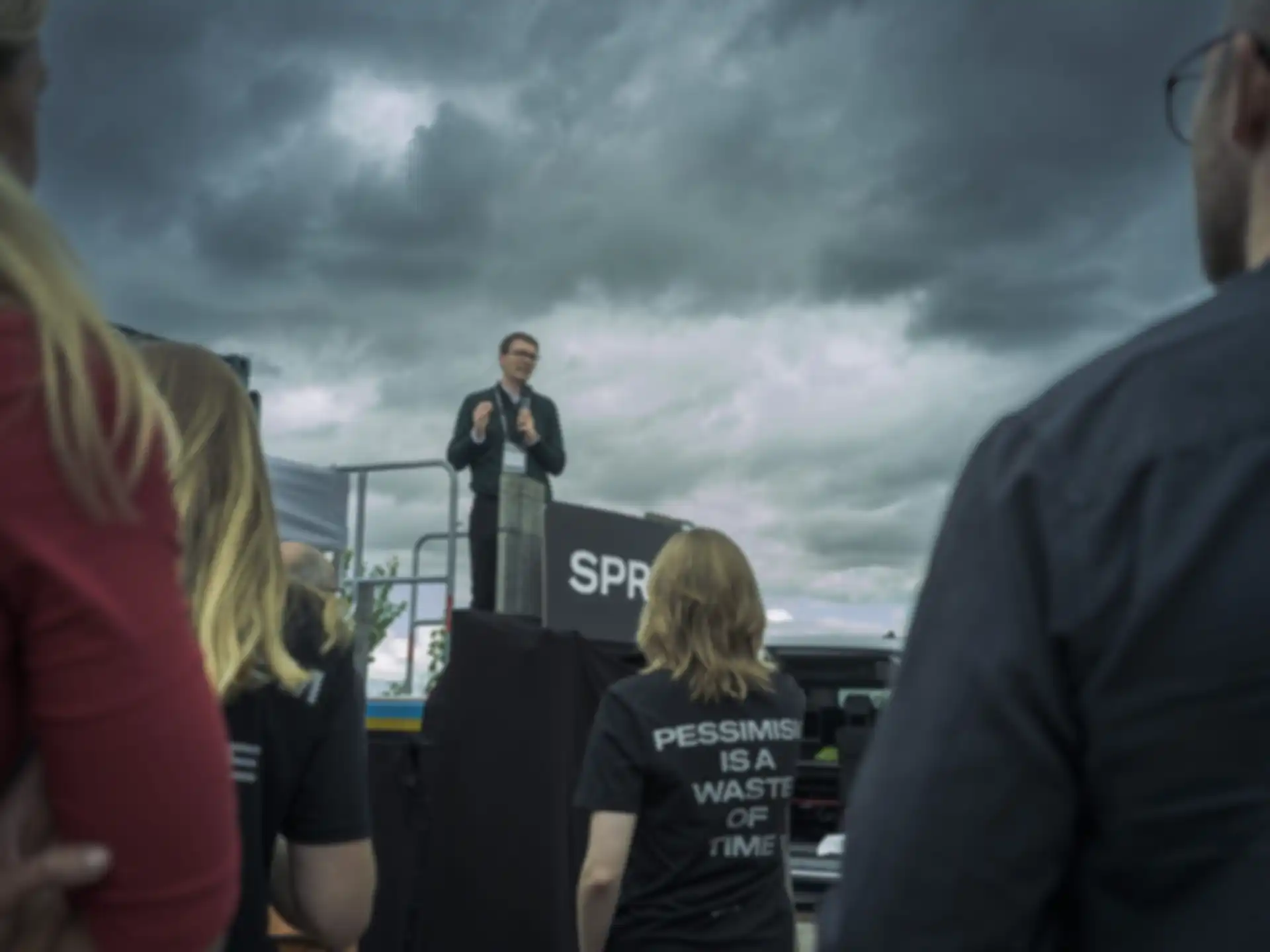 A person with a microphone is speaking to the audience from a balcony