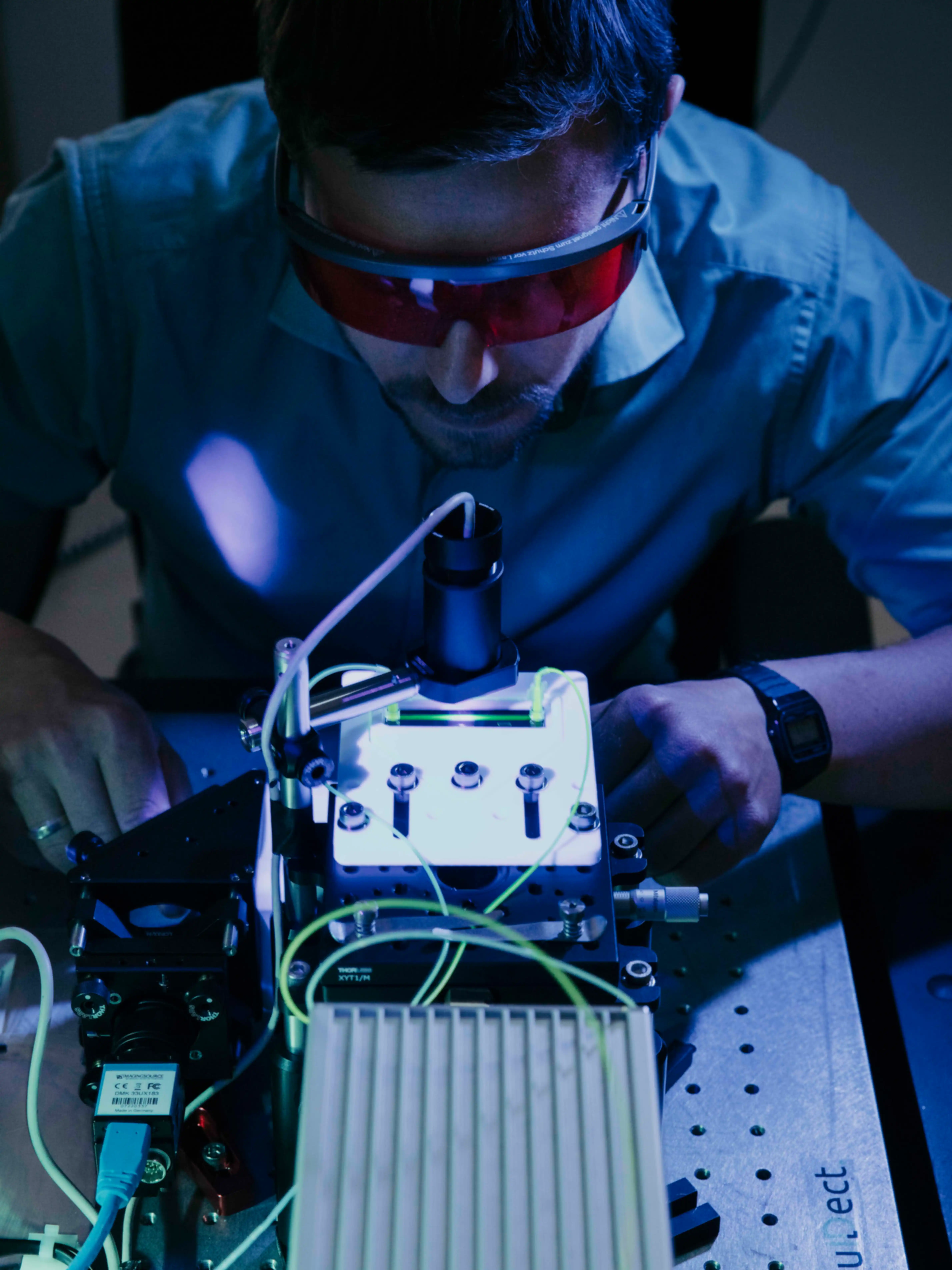 Ein Mann mit roter Schutzbrille bearbeitet eine technische Apparatur