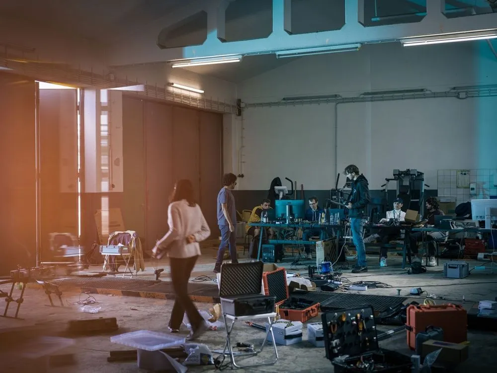 Personen arbeiten in einer Halle an den Dronen und esstehen dort viele technische Geräte